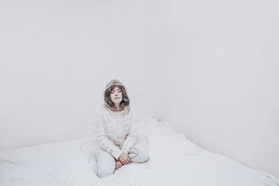 Bored woman with eyes closed sitting on duvet in confined place