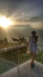 Rear view of woman standing on mountain against sky