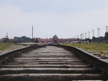 Railroad track leading towards city against clear sky