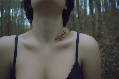 Midsection of woman wearing bra standing in forest