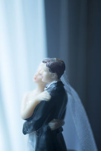 Close-up of wedding cake figurine on table by window at home
