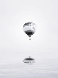 Hot air balloon flying over sea against clear sky