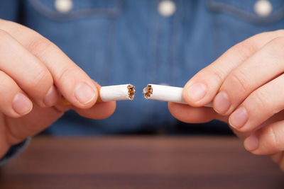 Midsection of woman breaking cigarette at table