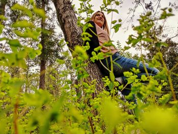 Woman standing by tree trunk