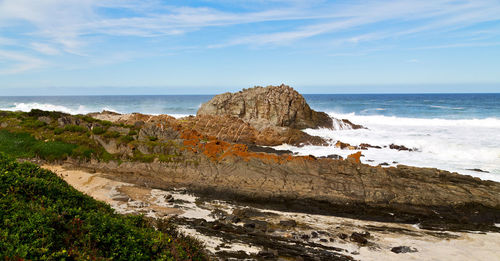 Rock formations on beach against sky