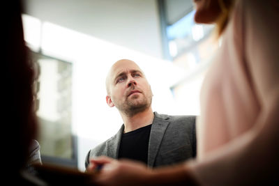 Confused businessman looking at female coworker in office meeting