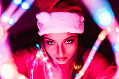 Portrait of young woman wearing santa hat with illuminated lights during christmas