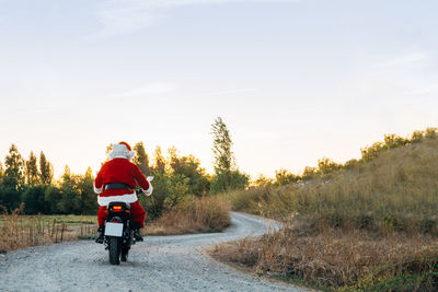 Rear view of man riding motorcycle on road against sky