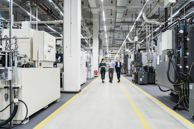 Businessman inspecting machinery with colleagues in electrical industry