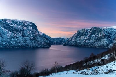 Scenic view of lake by snowcapped mountains against sky during sunset