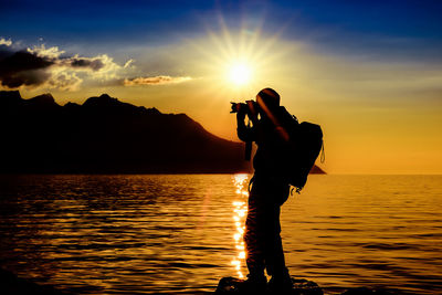 Silhouette of man taking photographs on beach