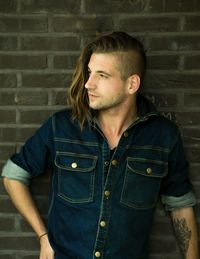 Young man looking away while standing against wall