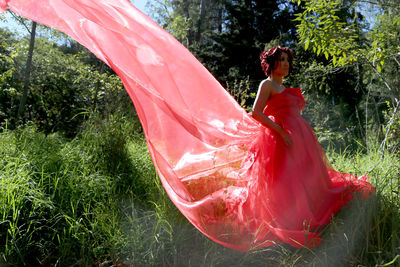 Woman wearing red gown standing on grassy field
