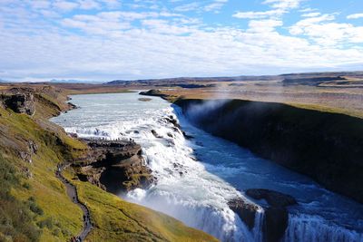 View of river in iceland against cloudy sky