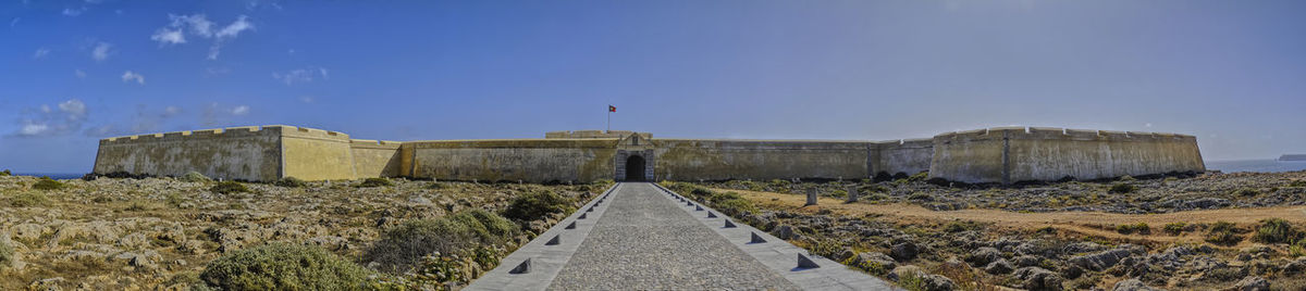 Panoramic view of road amidst buildings against clear blue sky