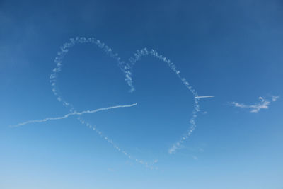 Heart shape with vapor trail against blue sky