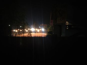 Illuminated street against sky at night