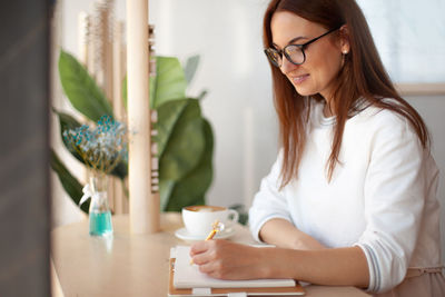 Smiling woman writing on diary while sitting at office