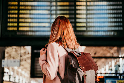 Rear view of woman wearing backpack standing on railroad station