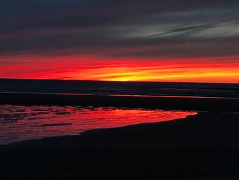 Scenic view of sea against dramatic sky during sunset