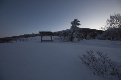 Scenic view of snowcapped field against clear sky during winter