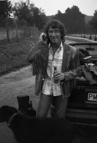 Happy man with dog standing by car on field