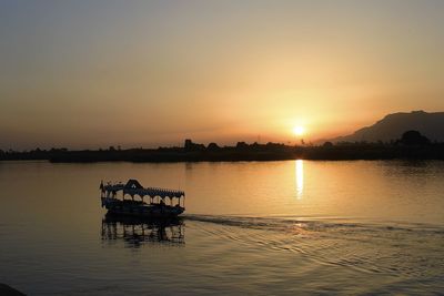 Silhouette boat in lake against sky during sunset