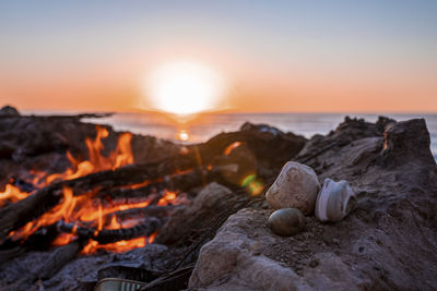 Bonfire with burning firewood during beautiful sunset at beach