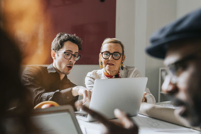 Businessman explaining female colleague over laptop at office