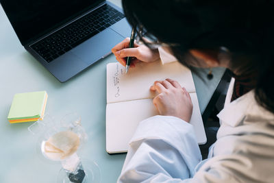 Young scientist writing on book over table in laboratory