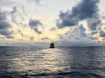 Boat sailing in sea against sky during sunset