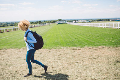 Side view of young woman walking at epsom downs racecourse during sunny day