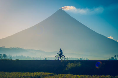 Man riding bicycle against sky