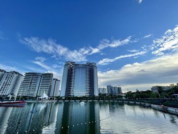 Modern buildings by river against sky in city