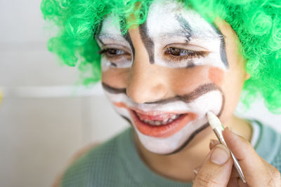 Mother painting her son's face like a clown