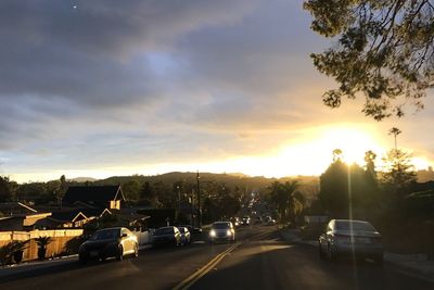 Cars on road against sky during sunset