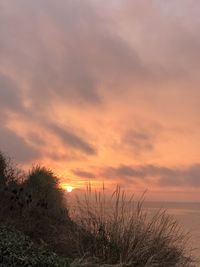 Scenic view of sea against dramatic sky during sunset