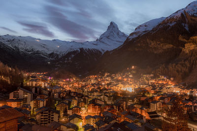 Aerial view of townscape and mountains against sky at night