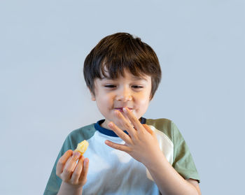 Portrait of boy eating food against white background