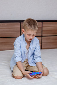 Boy looking away while sitting on bed at home