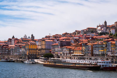 View of buildings at waterfront against cloudy sky