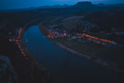 High angle view of illuminated city by river against sky