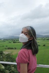 Side view of woman standing on field against sky