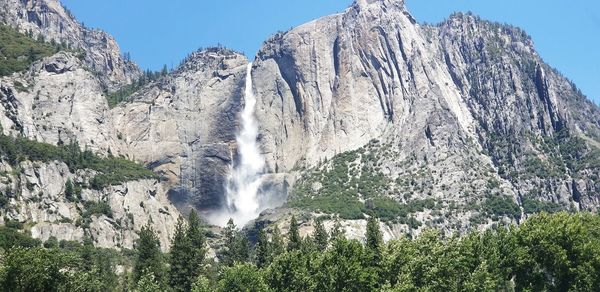 Low angle view of waterfall against clear sky