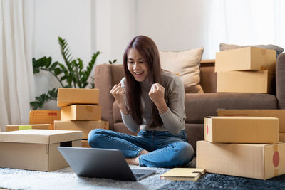 Young businesswoman clinching fist while using laptop at home