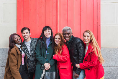 Group of excited multiracial friends having fun in city while standing looking at camera on street