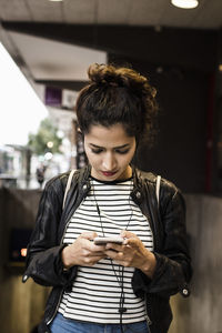 Woman listening music through smart phone in city