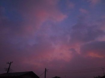 Low angle view of silhouette power lines against sky during sunset