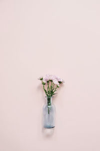 Beautiful blue glass vase with small pink bouquet on pink background.