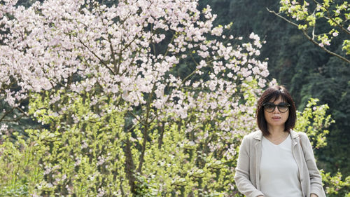 Portrait of beautiful young woman standing by flowers